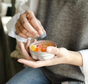 Woman reaching for cannabis gummies in tin